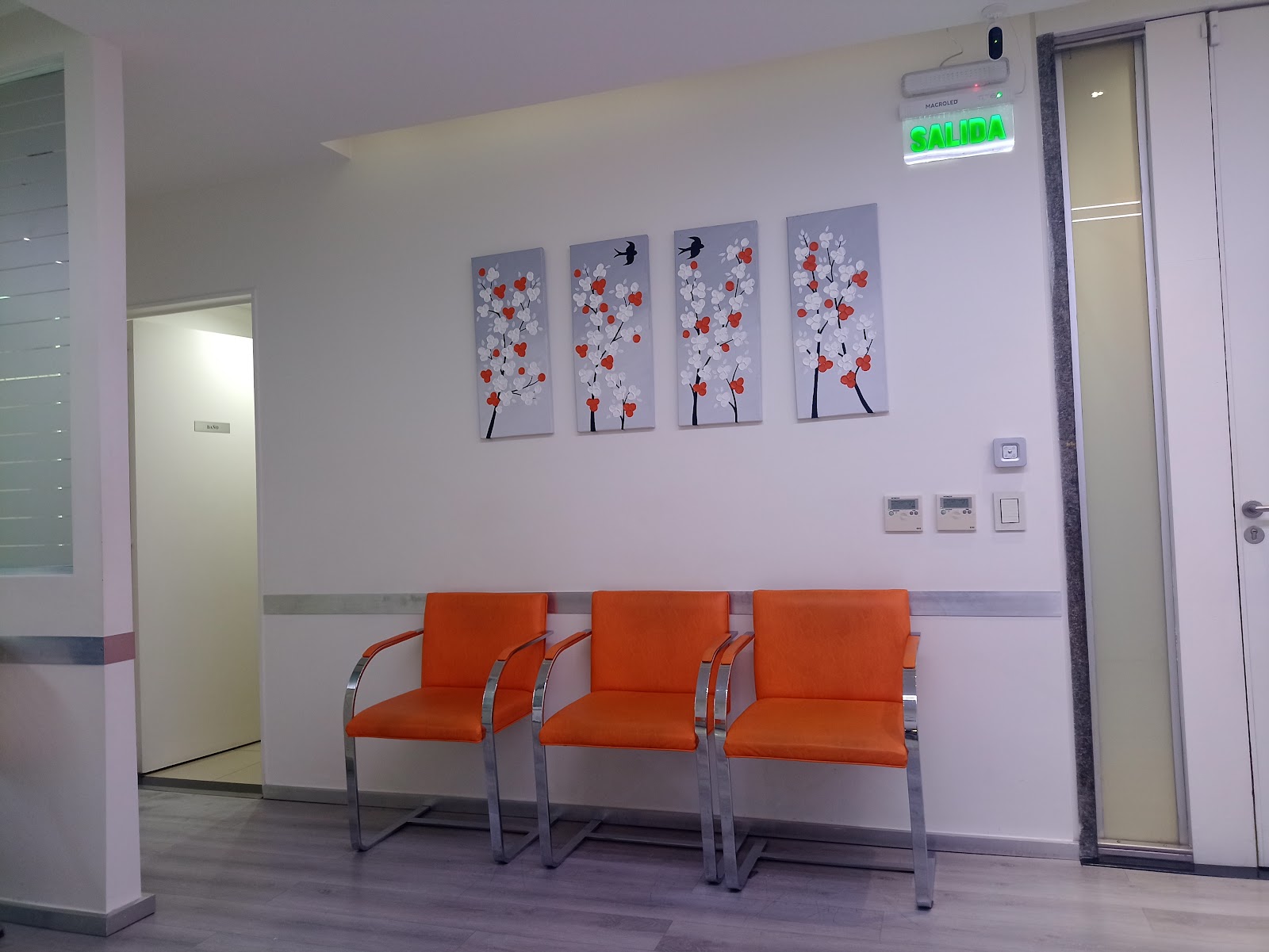 Sala de espera del Centro Odontológico, con sillones naranjas y cuadros florales